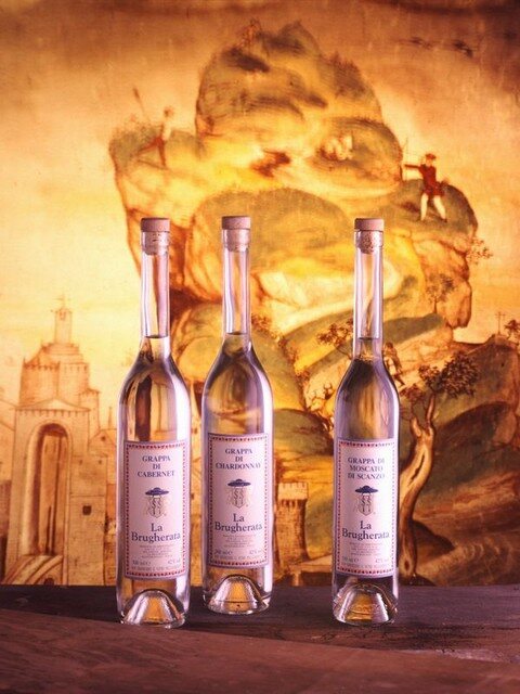 Tre bottiglie di distillato davanti a un fondale dorato